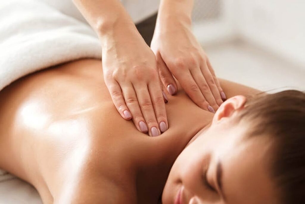 Top 5 Bestselling Massage Creams of 2023 on a wooden table with a backdrop of essential oils and herbs
